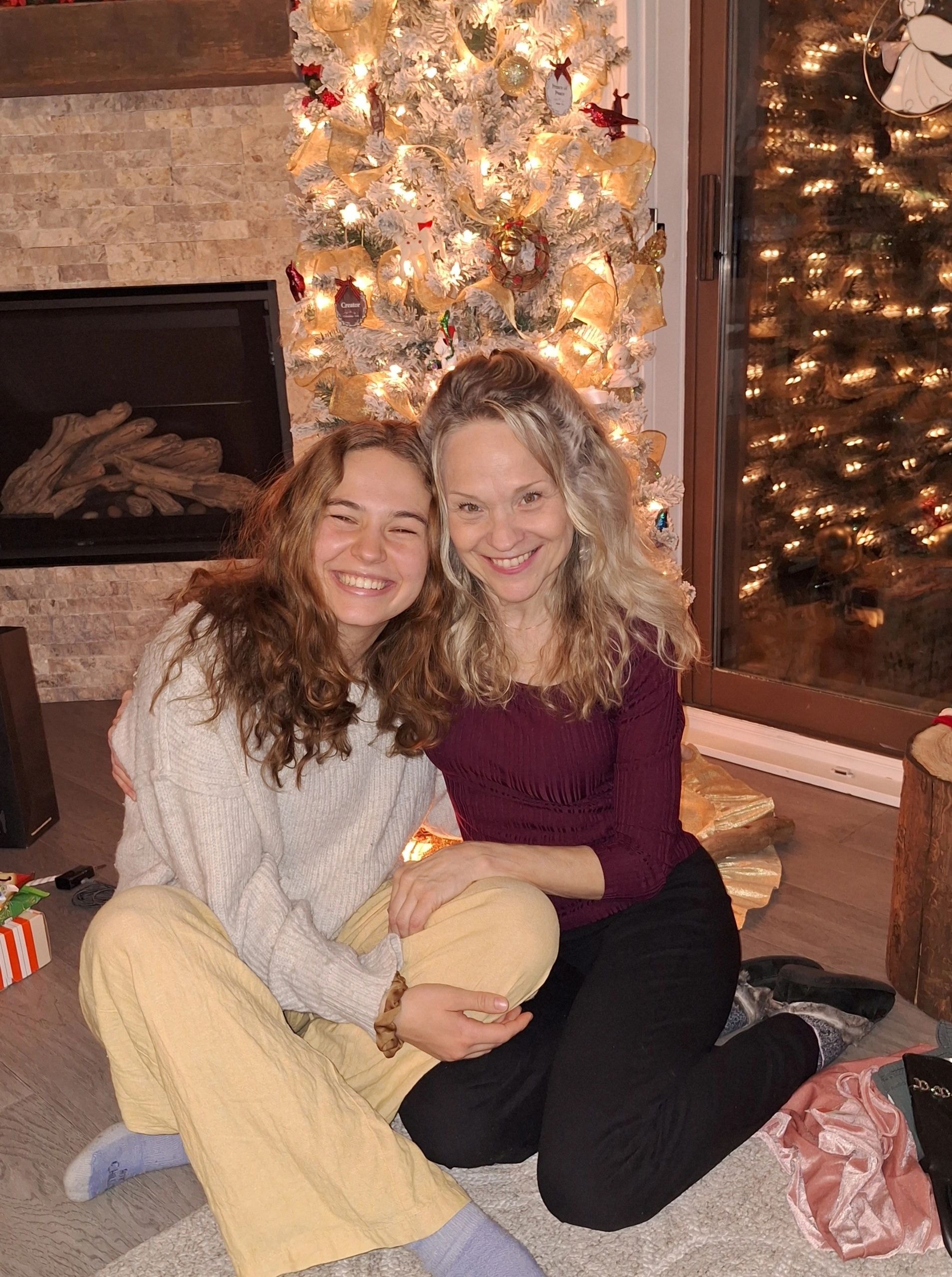 Joanne and her daughter Alyssa smiling together by a Christmas tree