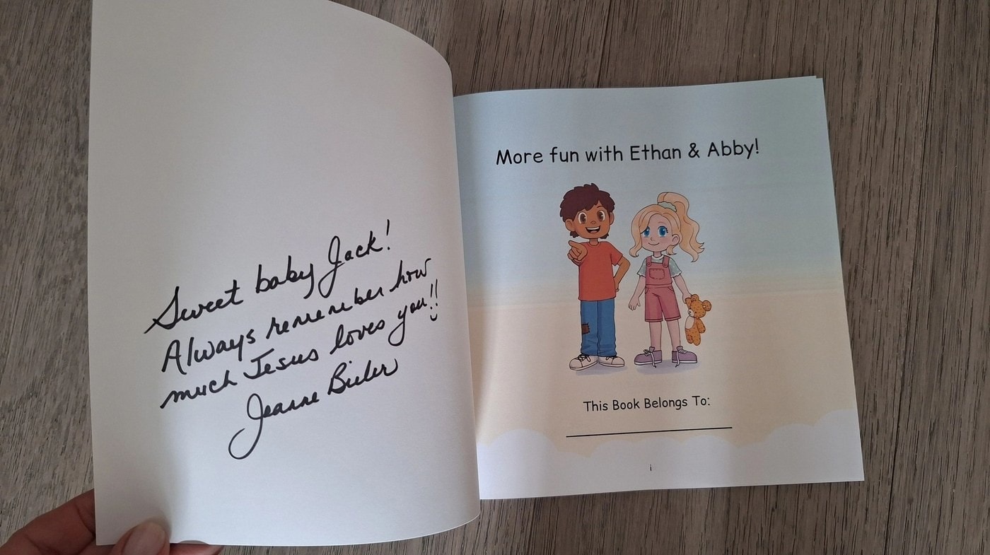 Open signed children's book with Ethan and Abby characters