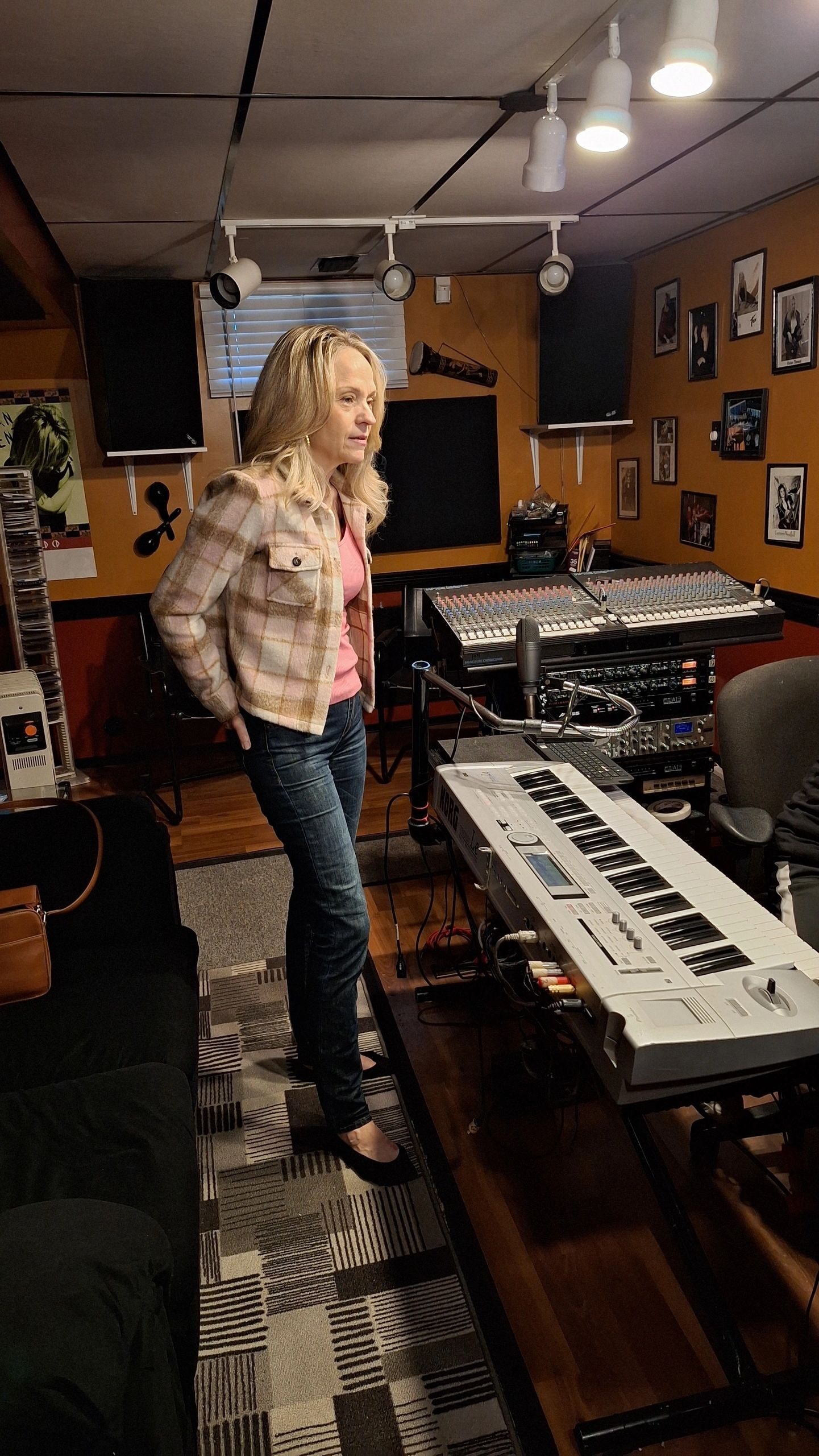Joanne standing in recording studio with mixing board and keyboard