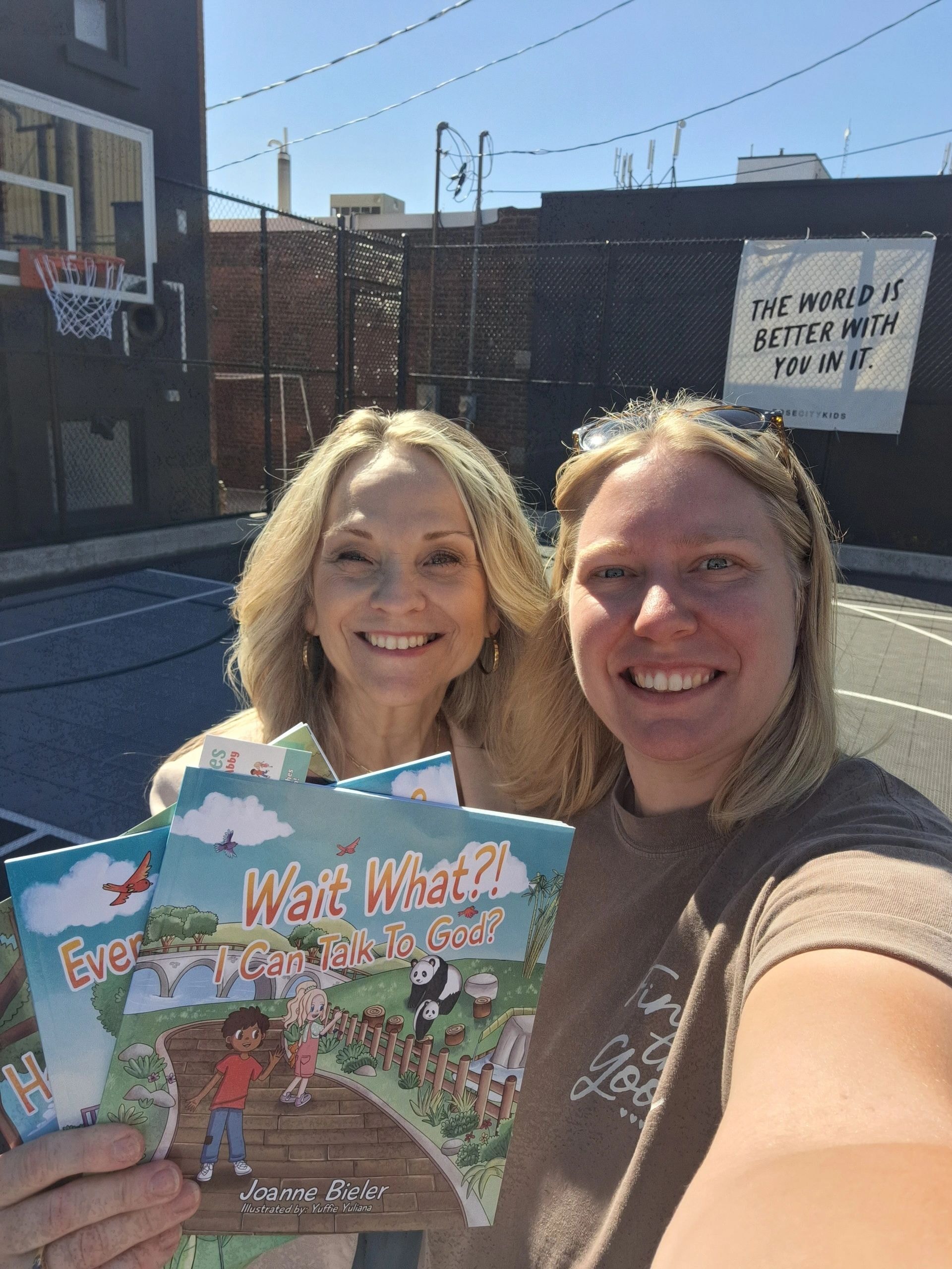 Joanne and Andrea holding books at basketball court at Rose City Kids Welland Ontario