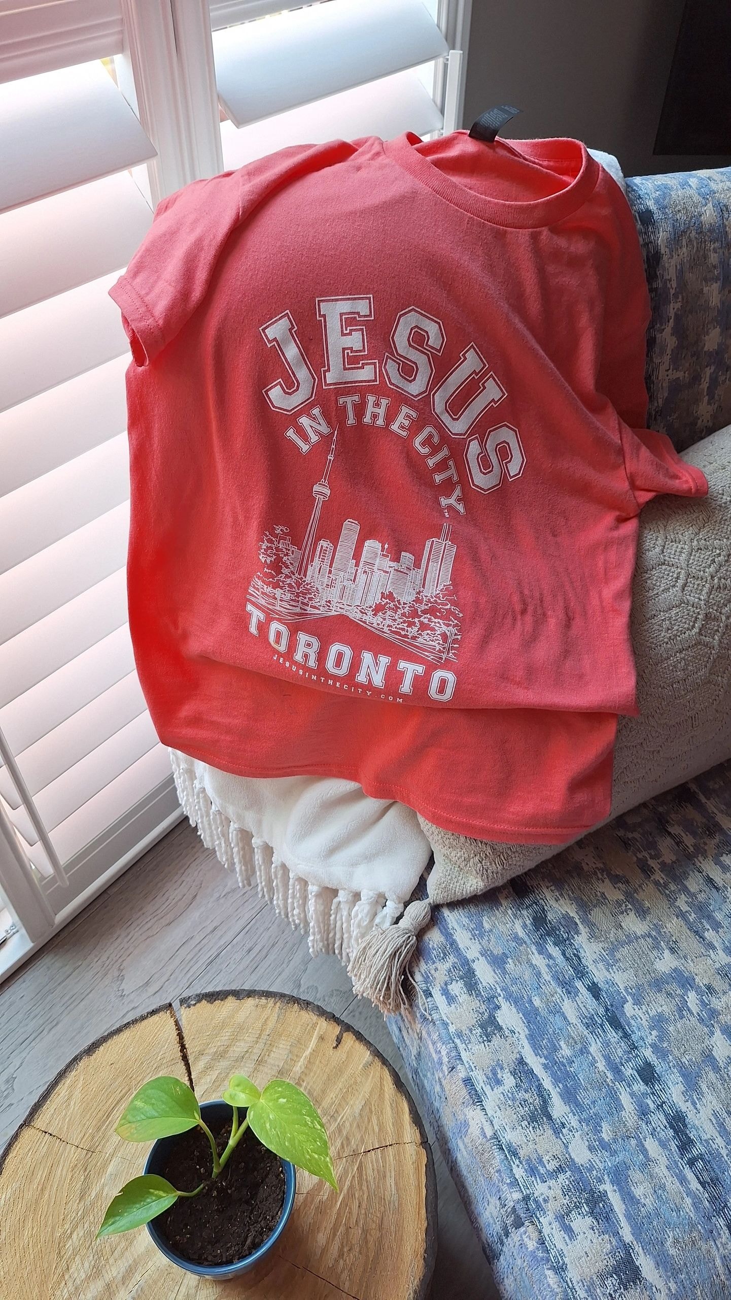 Jesus in the City Toronto red t-shirt with CN Tower skyline graphic on a couch