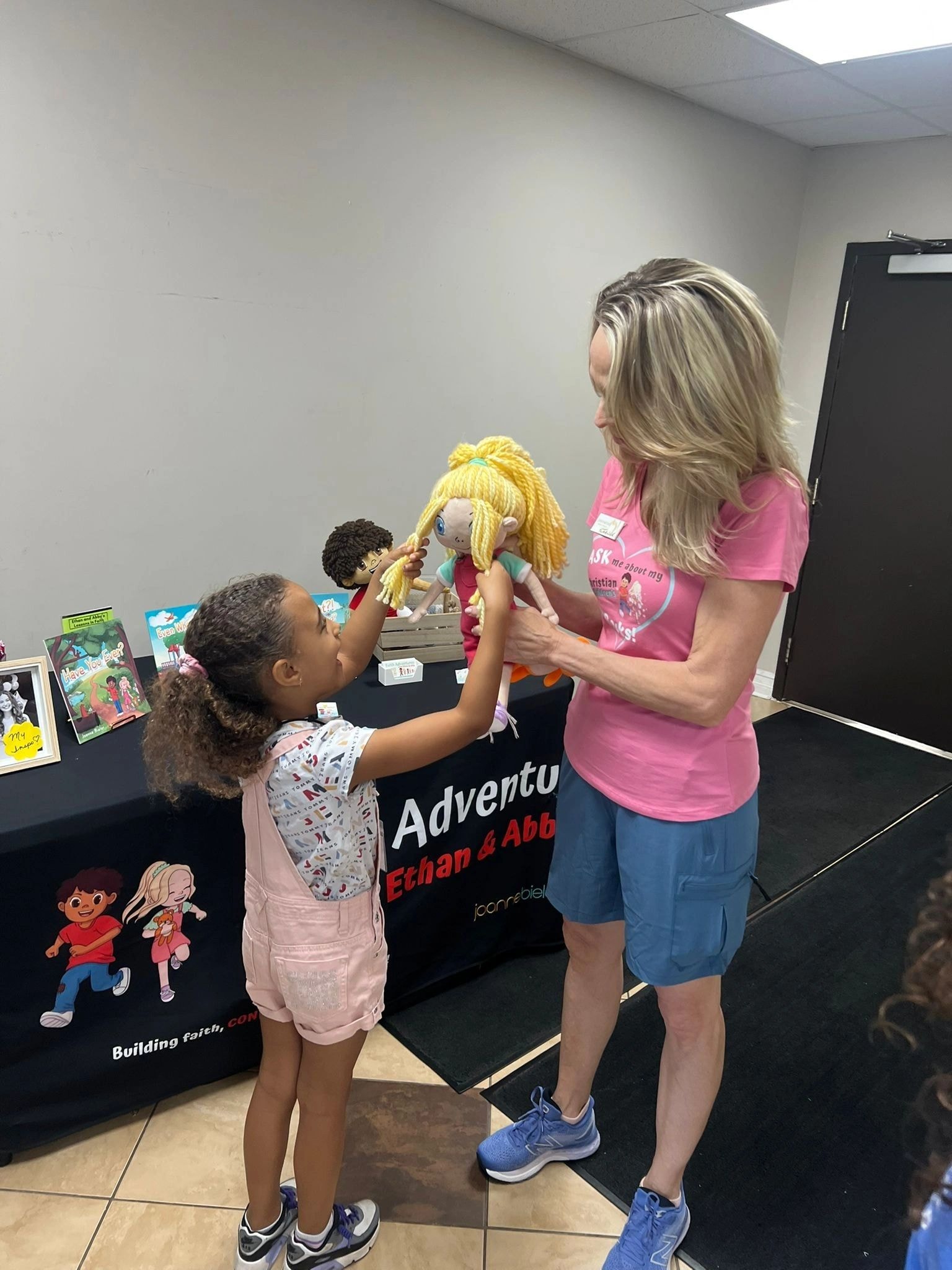 Joanne showing Abby doll up close to a young girl at VBS