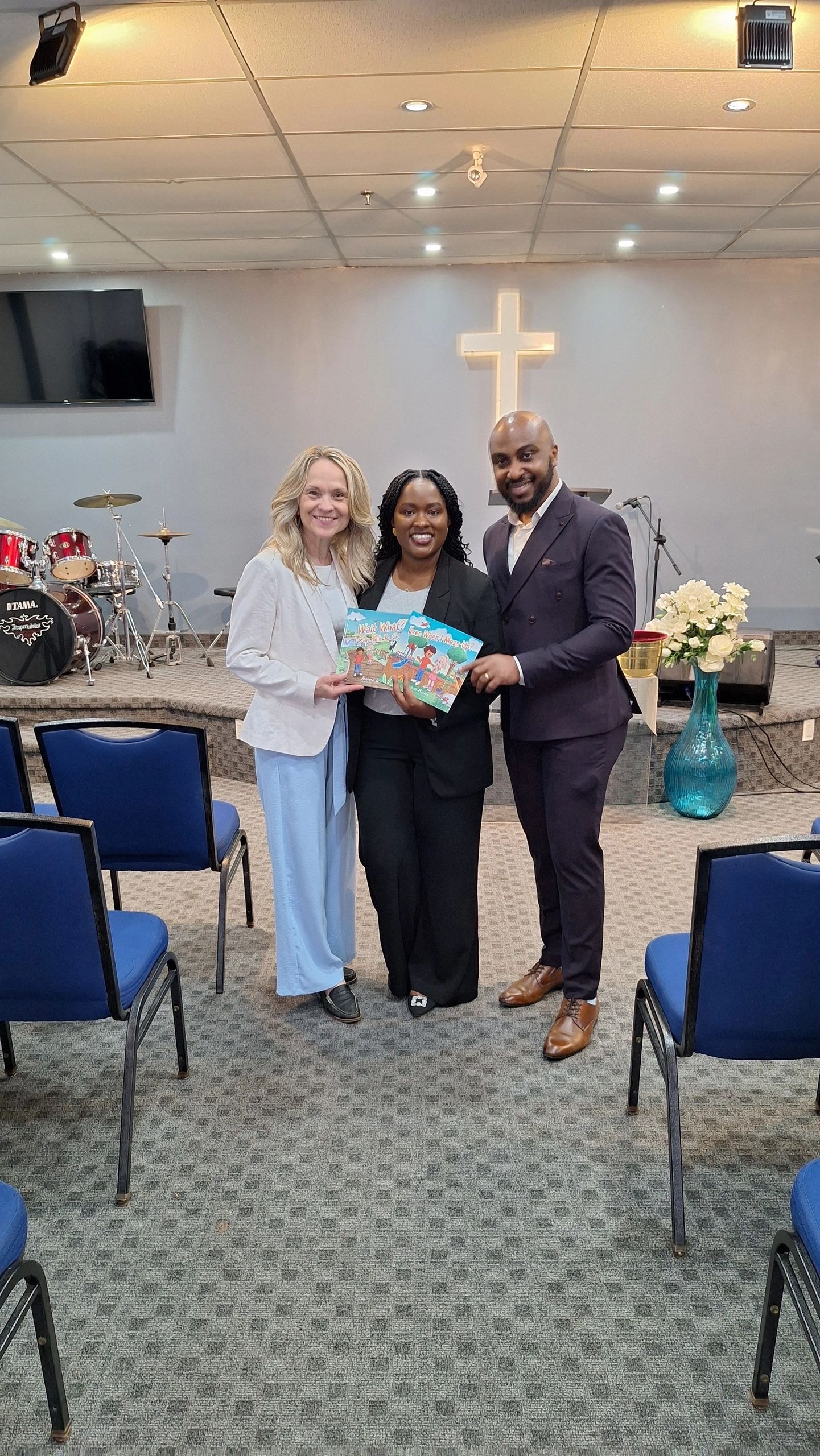 Joanne with three people holding Faith Adventures books at MCG Outreach Ministry church