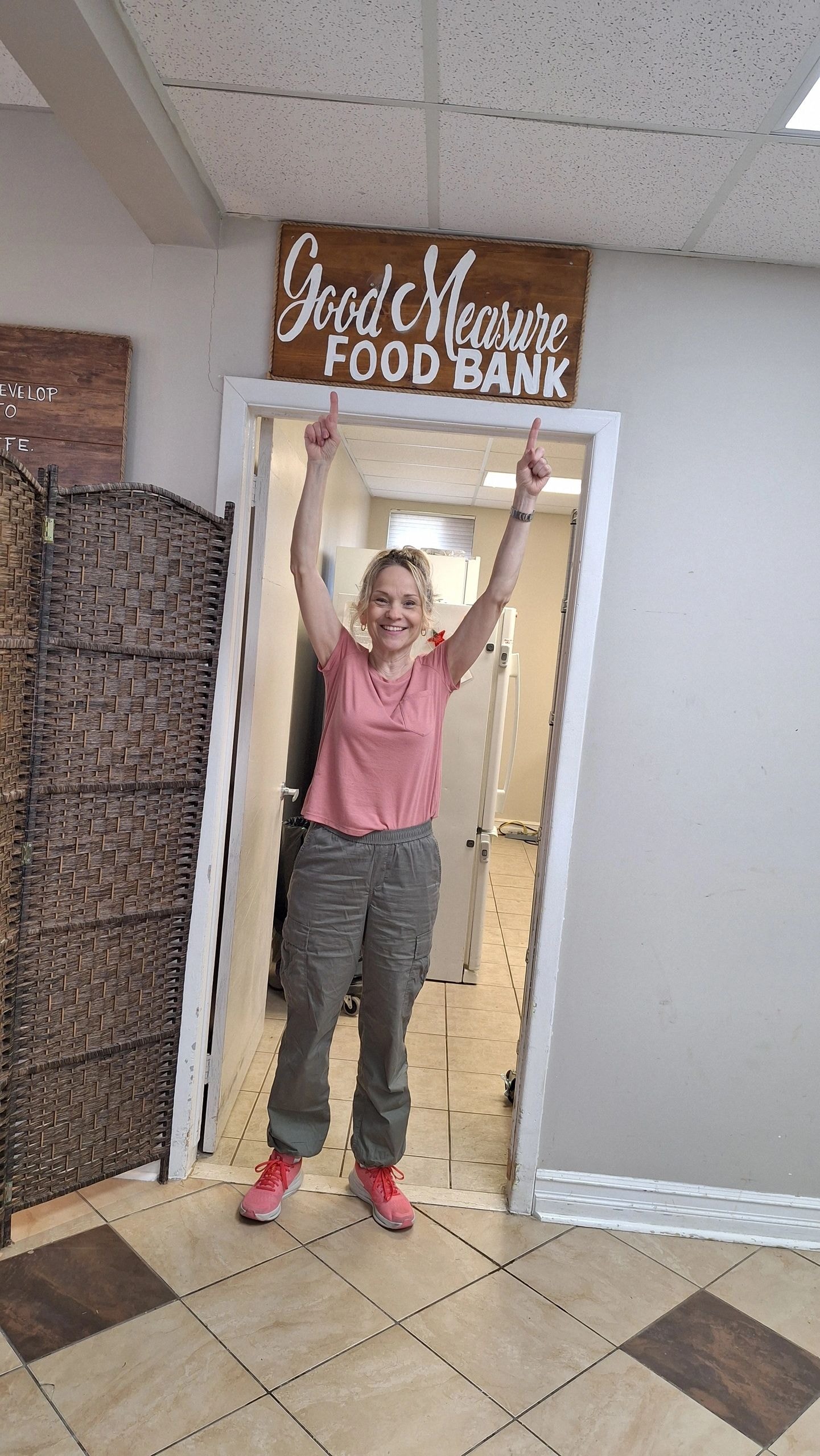 Joanne celebrating at Good Measure Food Bank doorway with arms raised at Christ For Life Ministries