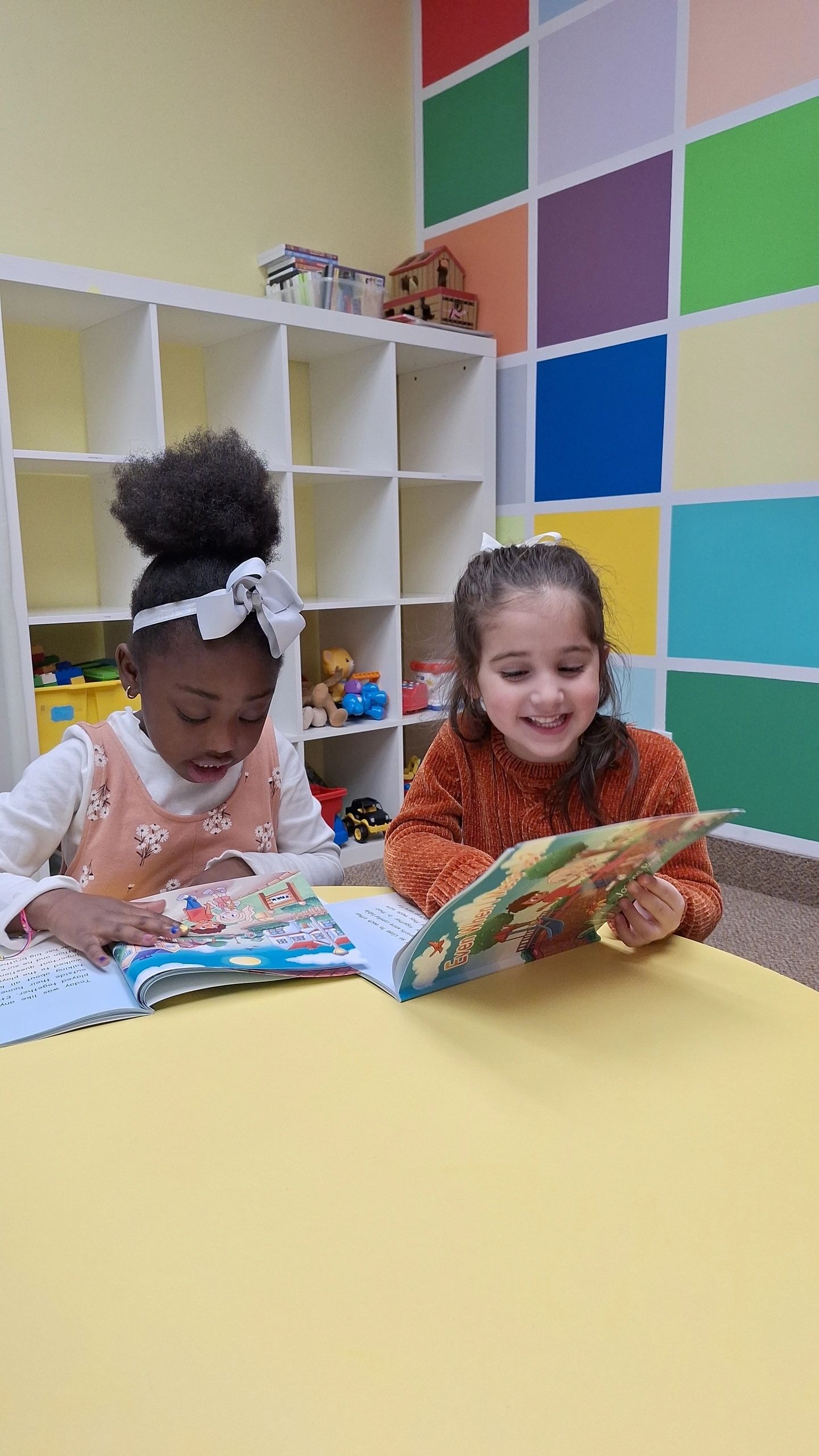 Two girls Lavignia and Leila reading Faith Adventures books together in a colorful playroom