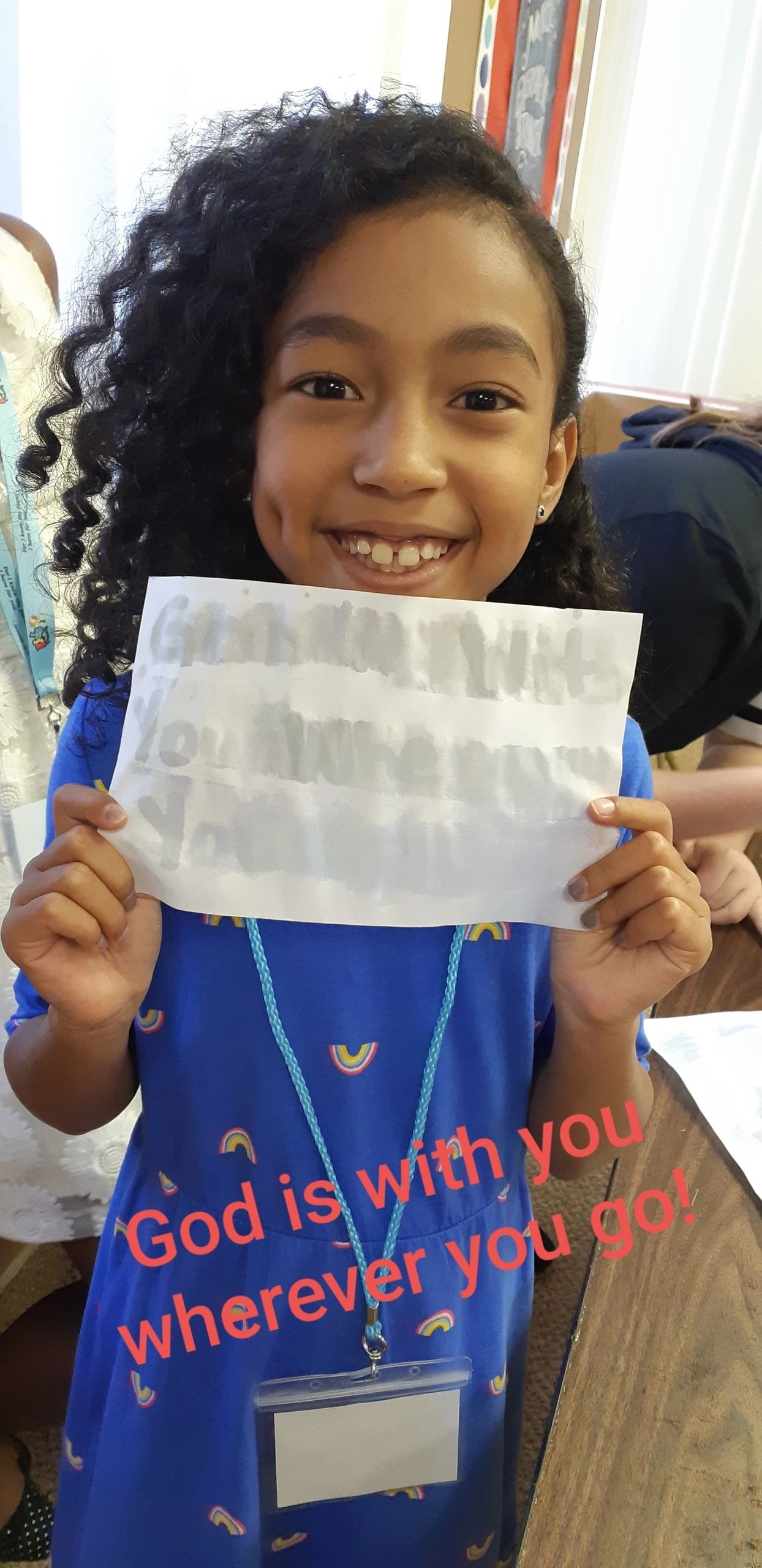 Young girl smiling and holding a secret message paper with God is with you wherever you go overlay
