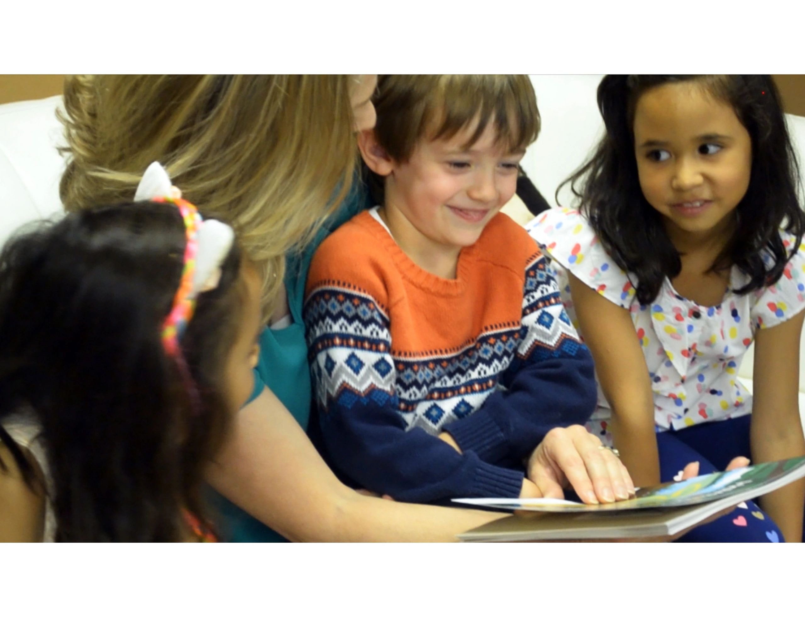 Joanne reading a Faith Adventures book to three children gathered close together on a couch