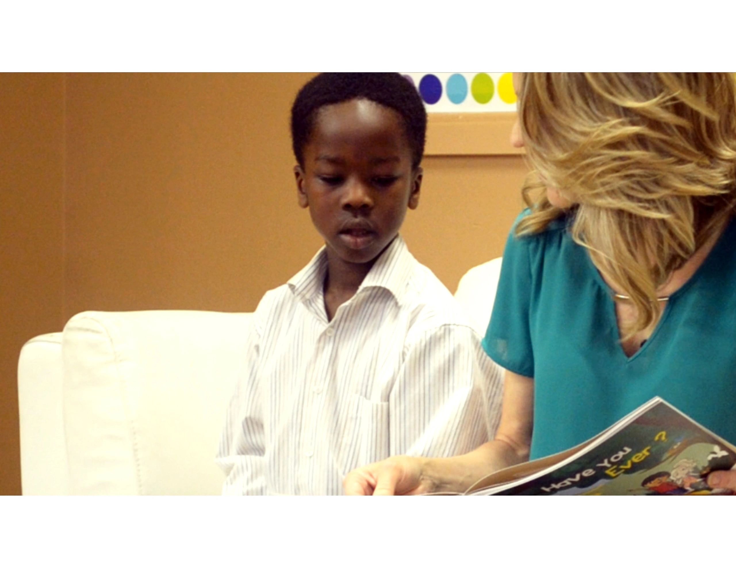 Young boy totally engaged reading Have You Ever? with Joanne during story time